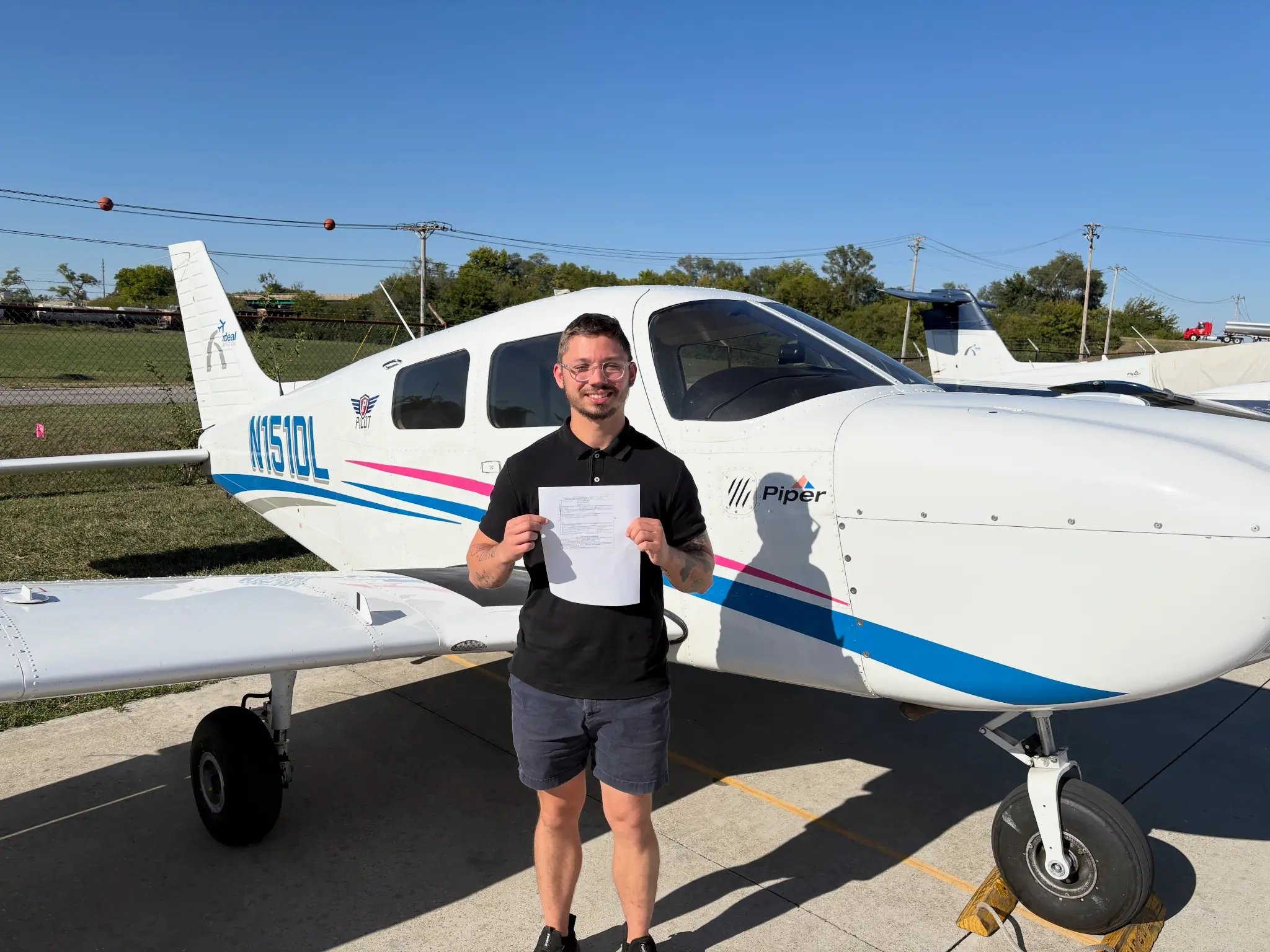 Student holding certificate in front of a Piper aircraft